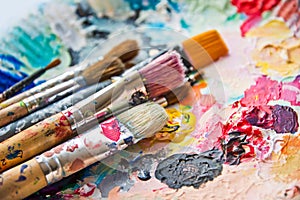 Used paint brushes on a colorful palette photo