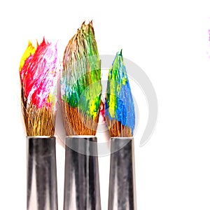 Used paint brushes of different colors, on a white background