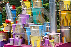 The used paint cans. Many multi-colored buckets with traces of paint on them