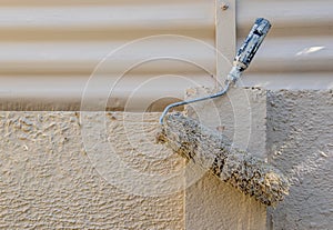 A used paint roller hangs on a wall