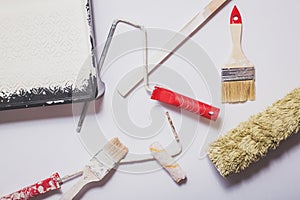 Used painting tools with red handles covered in warm white paint