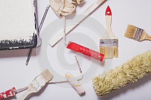 Used painting tools with red handles covered in warm white paint