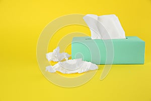 Used paper tissues and box on yellow background