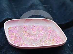 Used pink coloured blue silica gel from a camera lens keeping box in plastic dish on house roof in sun drying process