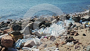Used plastic bottles lying on seashore near stones