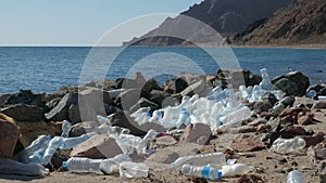 Used plastic bottles lying on seashore near stones