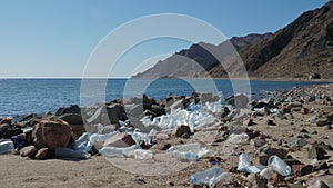 Used plastic bottles lying on seashore near stones