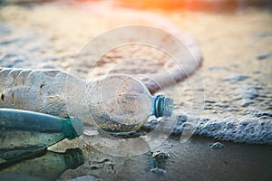 Used plastic bottles on sandy beach at morning or sunset light