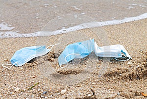 Used protective face masks discarded to ocean, sea plastic pollution concept