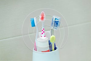 Used and ruined toothbrushes in a white holder on a neutral background