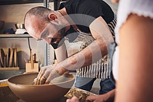 It used to be mud but not anymore. a young man and woman working with clay in a pottery studio.