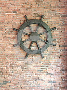 Used to rudder the old wooden boat on the background of red brick cement wall.steering wheel vintage wooden with a sea ship