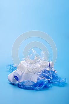 Used unsorted garbage in a pile. Bottles, bags and paper on blue background. Waste sorting. Place for text