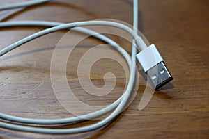 Used USB plug with cable on the wooden floor.