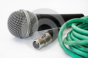 Used vocal microphone with old green xlr cable on the white back