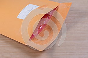 Used yellow blank envelope with transparent bubble wrap or packaging shockproof on wooden table.