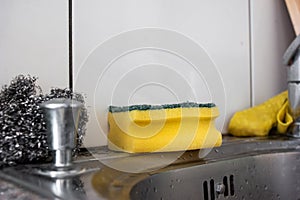 Used yellow kitchen cleaning sponge set on the side of the sink shallow depth of field