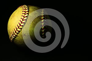 A used yellow softball isolated on a black background.