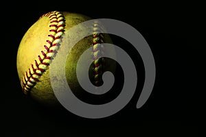 A used yellow softball isolated on a black background. photo