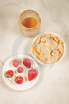 Useful breakfast with strawberry, flakes and honey/useful breakfast with strawberry, flakes and honey on a white marble background