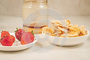 useful breakfast with strawberry, flakes and honey/useful breakfast with strawberry, flakes and honey on a white table, selective