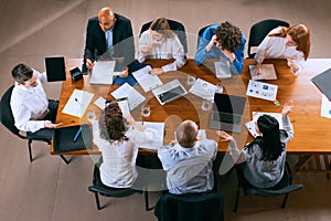 Useful info, news. Aerial view of young multiethnic people talking, working with colleagues, co-workers at office