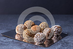 Useful sweets - homemade energy balls of dried fruits, oatmeal and nuts, on foil and on a dark background.