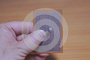 A user mounting a transistor on a brown colored protoboard with a wooden background