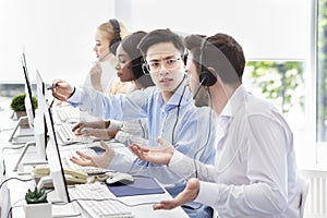 User support service concept. Hotline operator helping his coworker at call centre