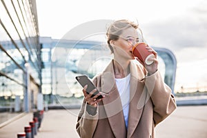 Usiness woman using phone near airport entrance