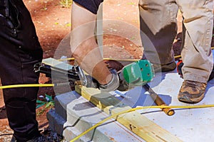 Using an air nail hammer, framer installs beams on a wooden frame photo