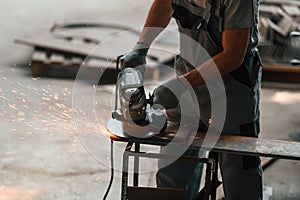 Using angle grinder. Close up view of man that is working at the factory