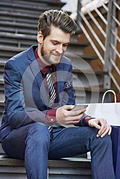 Using an app to find great boutiques closest to him. a well dressed young man using his phone on a shopping spree.