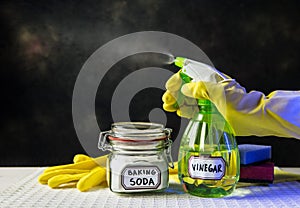 Using baking soda Sodium bicarbonate and white vinegar for home cleaning. White vinegar in spray bottle and baking soda in glass j