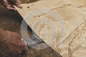 Using a blade scrapper or putty knife to remove old vinyl tiles from the floor. Home renovation concept