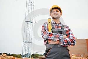 Using bricks. Young construction worker in uniform is busy at the unfinished building