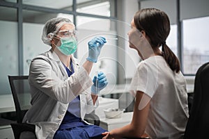 Using a cotton swab, the laboratory assistant takes the contents of the nasopharynx from the client to detect the photo