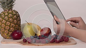 Using a digital tablet near fresh fruits.