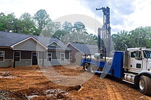 Using a drilling machine workmen drill water well in suburban yard for artesian water.