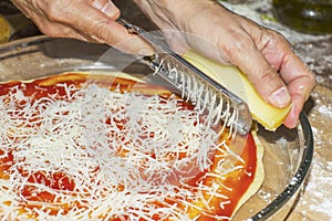 Using a grater to grate cheese in pizza