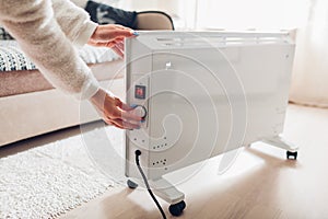 Using heater at home in winter. Woman regulating temperature on heater. Heating season