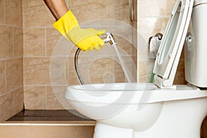 Using a hose to spray water to clean the toilet bowl