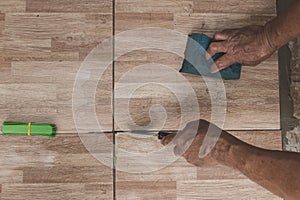 Using a joint putty knife to clean or scrape the edges of the tiles while holding a sponge. Tile laying and home renovation concep