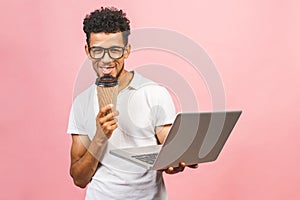 Using laptop. Portrait of handsome casual african american young man drinking coffee while holding laptop computer isolated