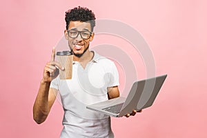 Using laptop. Portrait of handsome casual african american young man drinking coffee while holding laptop computer isolated