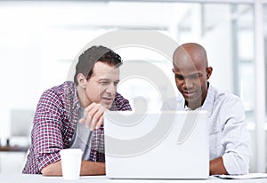 Using the latest design applications. Two professionals working together on a project on a laptop while sitting at a