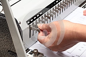 Using the left hand adorned gear to penetrate the paper. Preparation for Binding