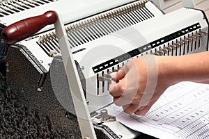 Using the left hand adorned gear to penetrate the paper. Preparation for Binding