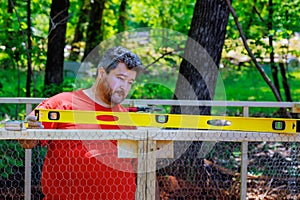 Using level worker levelling new wooden domestic chicken coop on farm build containing the metal mesh