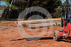 Using a lift manipulator, a construction site worker unloads a delivery of wooden building material